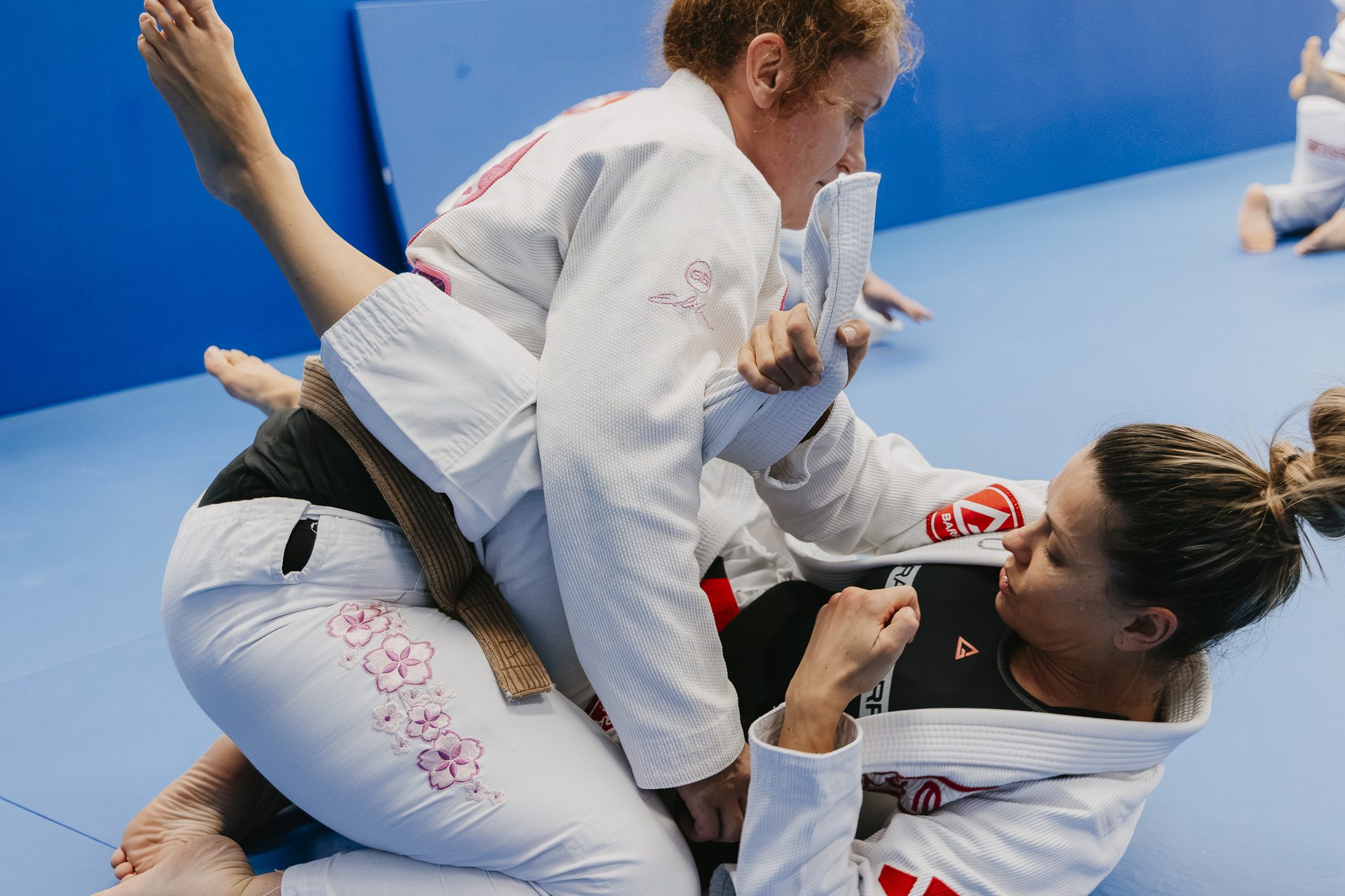 Two Gracie Barra women rolling during training